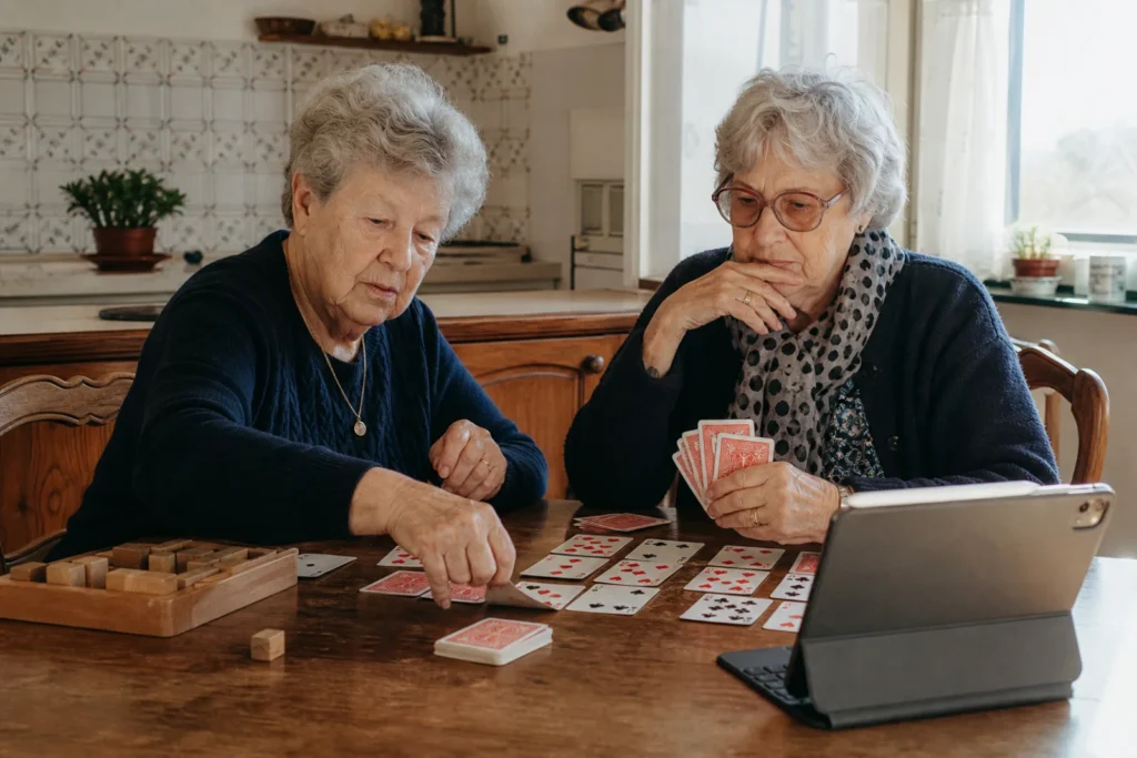 Deux femmes âgées jouent aux cartes autour de leur table de cuisine.